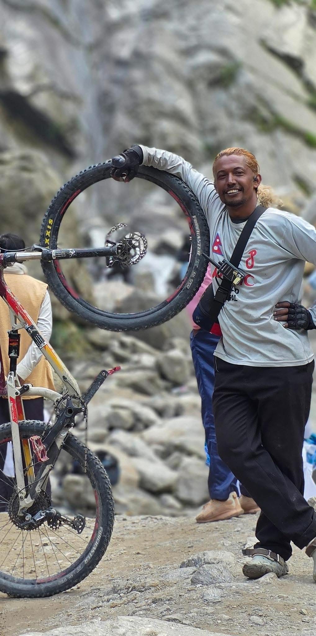 Carrying bike wheel through rocky river terrain